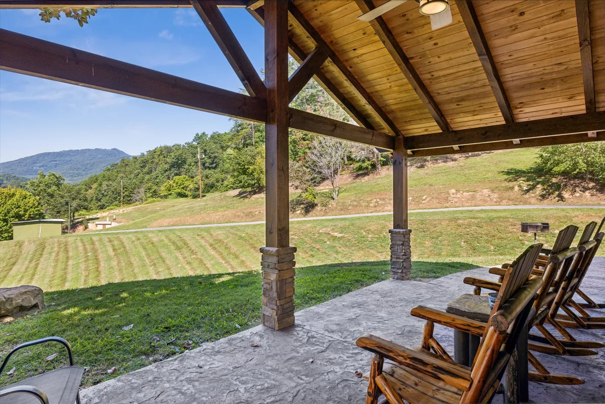 A peaceful view of the mountains serves as the backdrop to a wooden structure with rocking chairs positioned perfectly to soak in the sunrise or sunset. The setting suggests relaxation, socializing, and an appreciation of scenic beauty.
