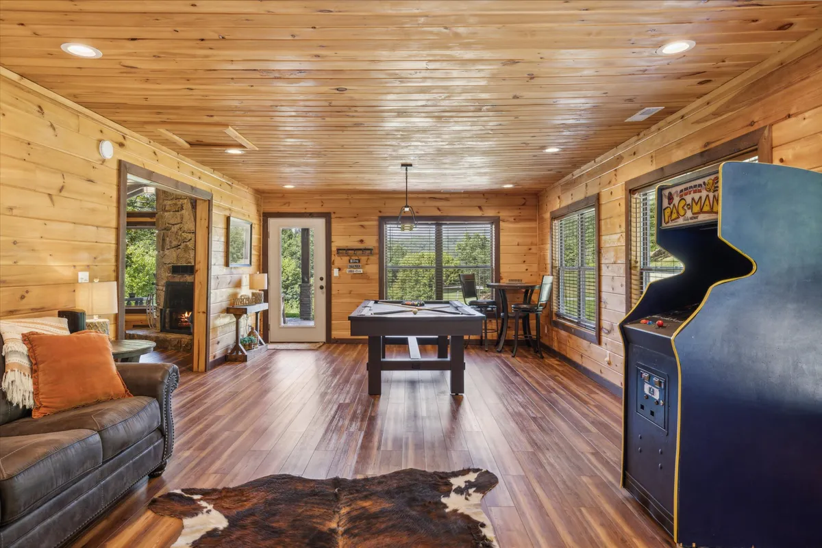A lively game room with a pool table, retro Pac-Man arcade game, comfortable sofa, and a cozy fireplace, all set in a family-friendly atmosphere ideal for play and bonding.