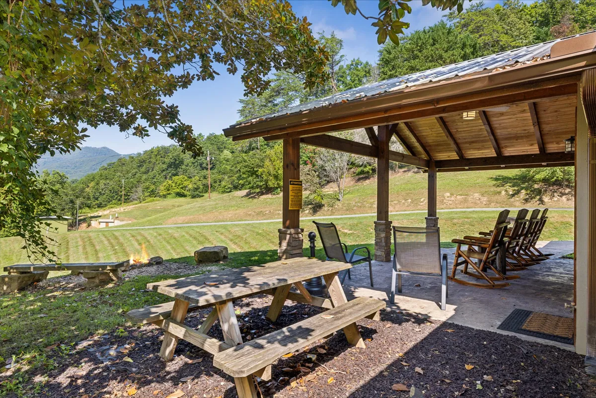 This image features a welcoming patio area with a picnic table and rocking chairs set against a breathtaking mountain view. The setup encourages outdoor dining, social gatherings, and relaxation in a tranquil natural setting. The scene captures the inviting atmosphere of the cabin’s exterior, perfect for groups to unwind and connect while immersed in the surrounding landscape.